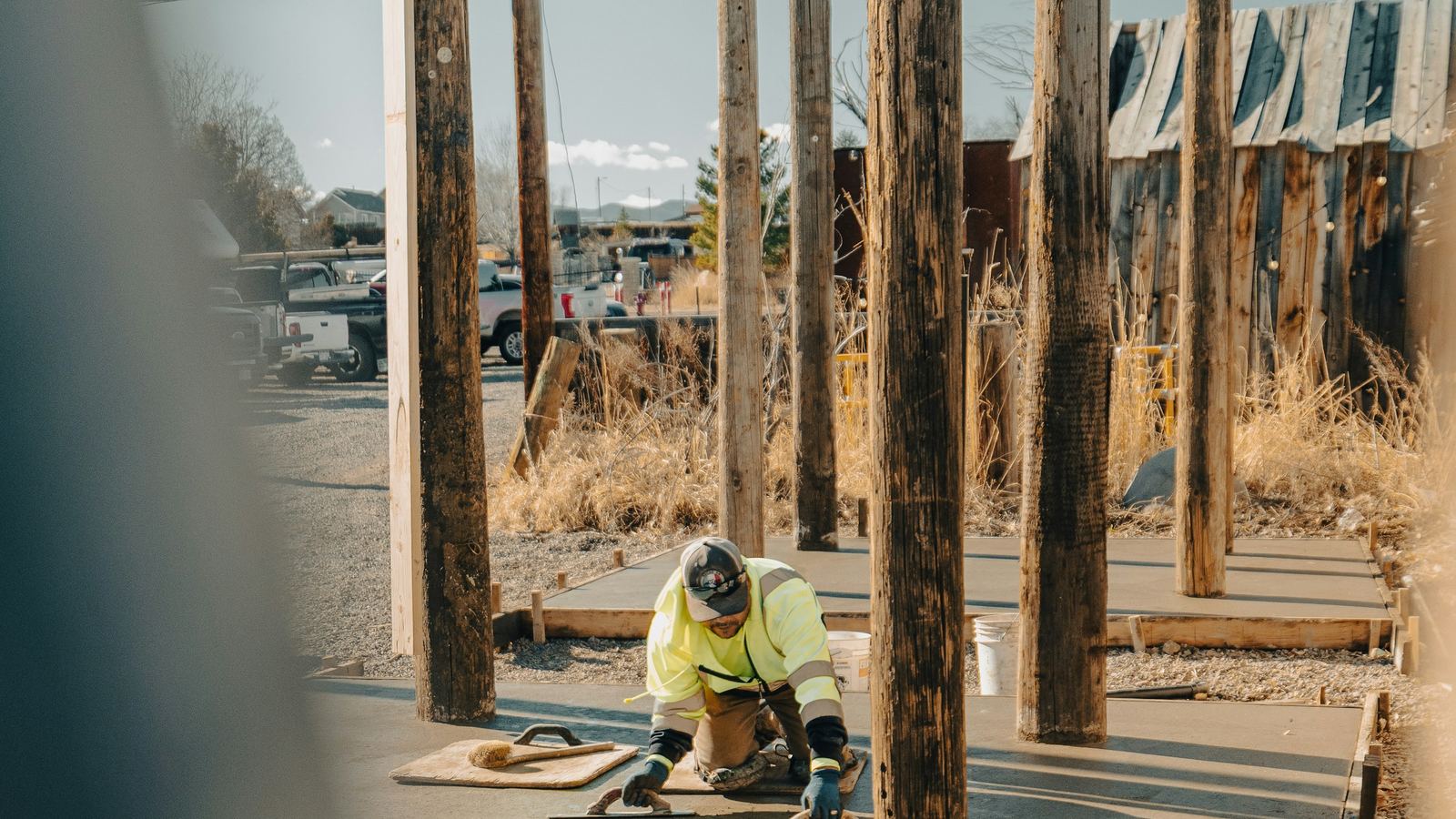 Worker finishing a wet concrete slab on a construction site.